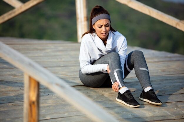 Young sportswoman experiencing pain in her leg while having sports training in nature