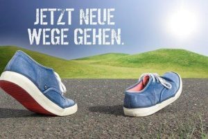 Jetzt neue Wege gehen - a pair of shoes on the ground with the sun in the background