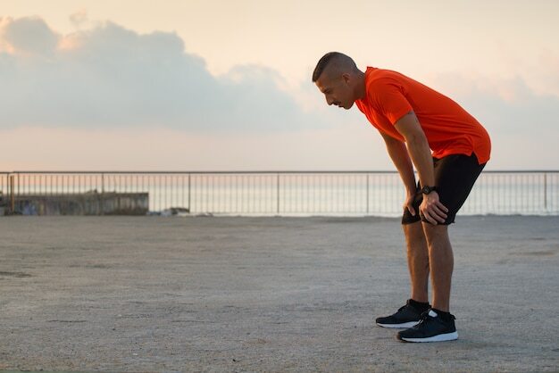 Tired male athlete having break after jogging