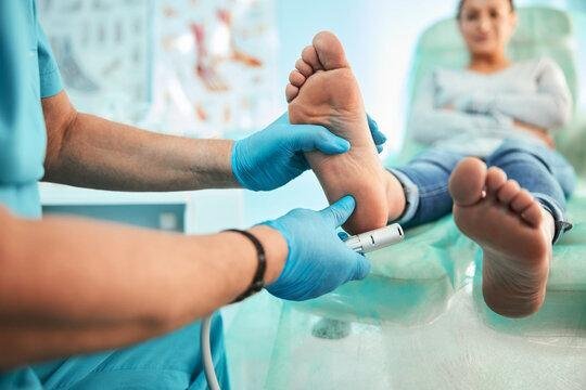 Podiatrist using special grinding equipment and making procedure polish for feet - a man getting his